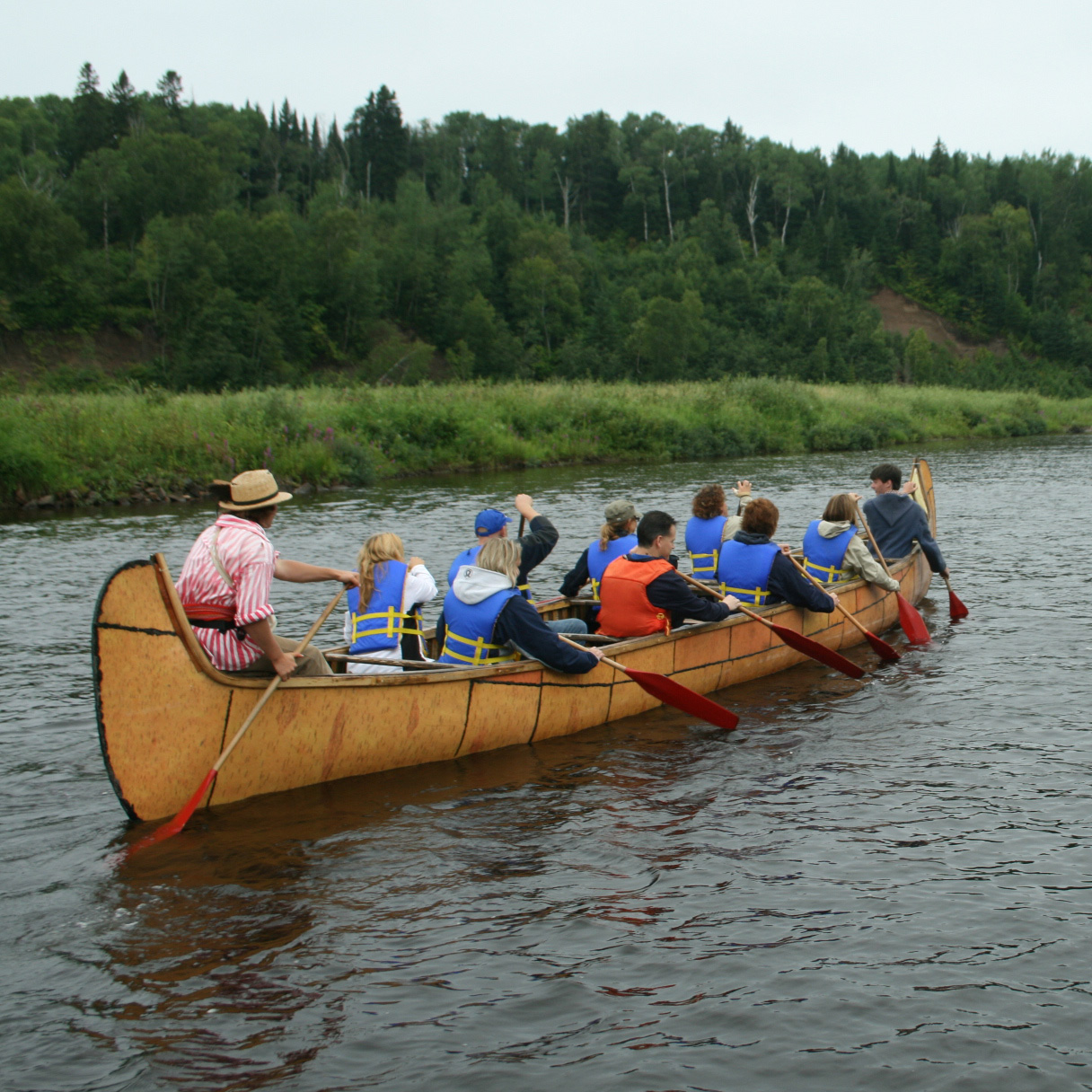 a group of people paddling a historic canoe